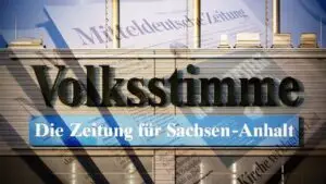 Logo der Zeitung Volksstimme mit dem Schriftzug Die Zeitung für Sachsen-Anhalt, vor Zeitungsseiten als Hintergrund.