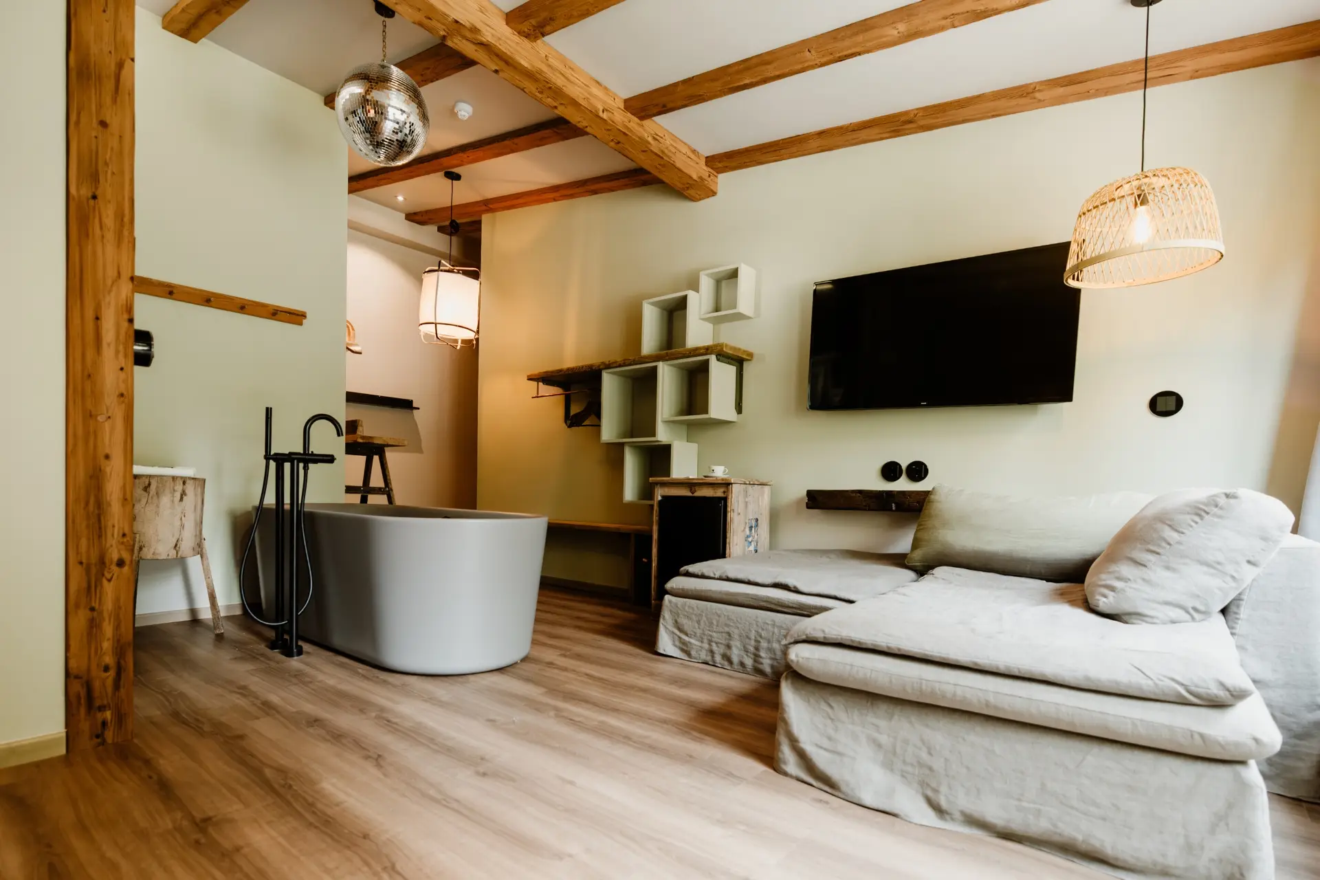 Moderne Wohnraumgestaltung mit Sofa, Badewanne und TV. Holzelemente und sanfte Beleuchtung schaffen eine einladende Atmosphäre.