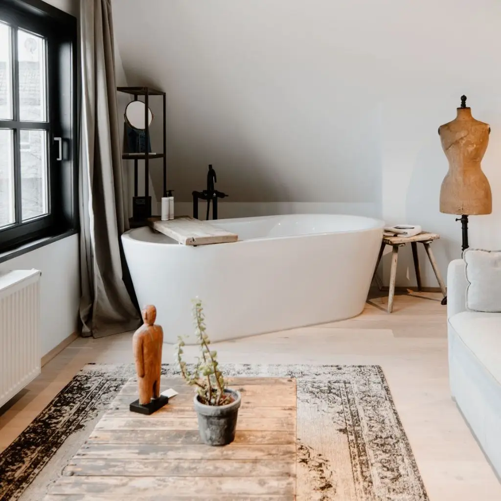 Modernes Badezimmer mit freistehender Badewanne, Holzregal, Pflanzen und einer glücklichen Atmosphäre. Sichtbare Fenster und Möbel.