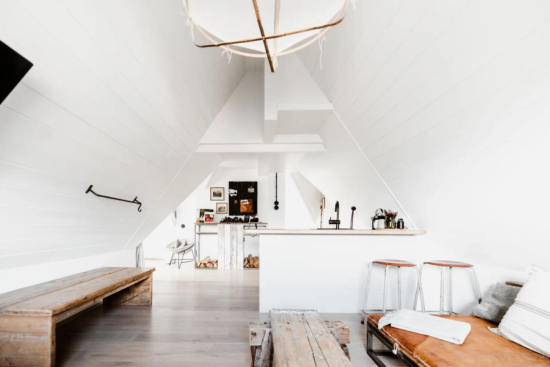Helle, moderne Dachwohnung mit einer offenen Küche, Holzstuhl, Holztischen und minimalistischer Einrichtung.
