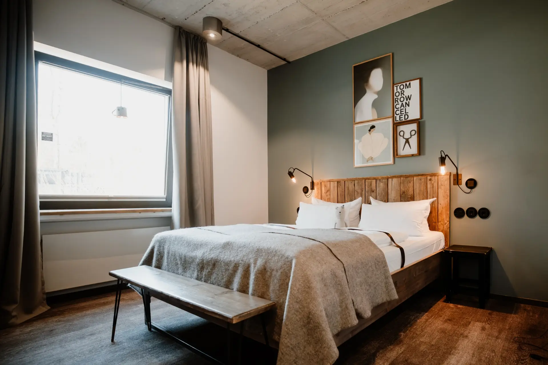 Gemütliches Schlafzimmer mit einem Doppelbett, Holzbank, Fenster und minimalistischer Kunst an der Wand. Helle, moderne Einrichtung.