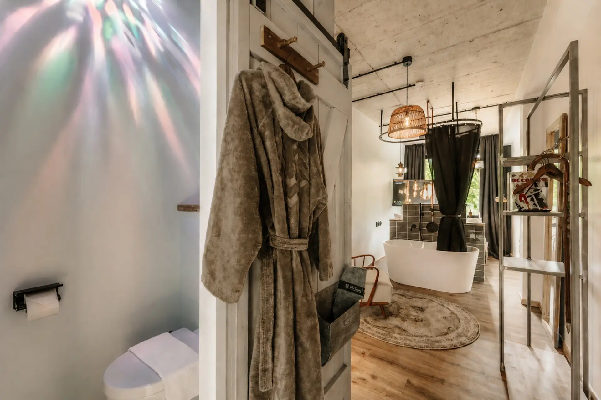 Badezimmer mit einem hellen Badezimmer und einer freistehenden Badewanne; ein Bademantel hängt an der Tür.