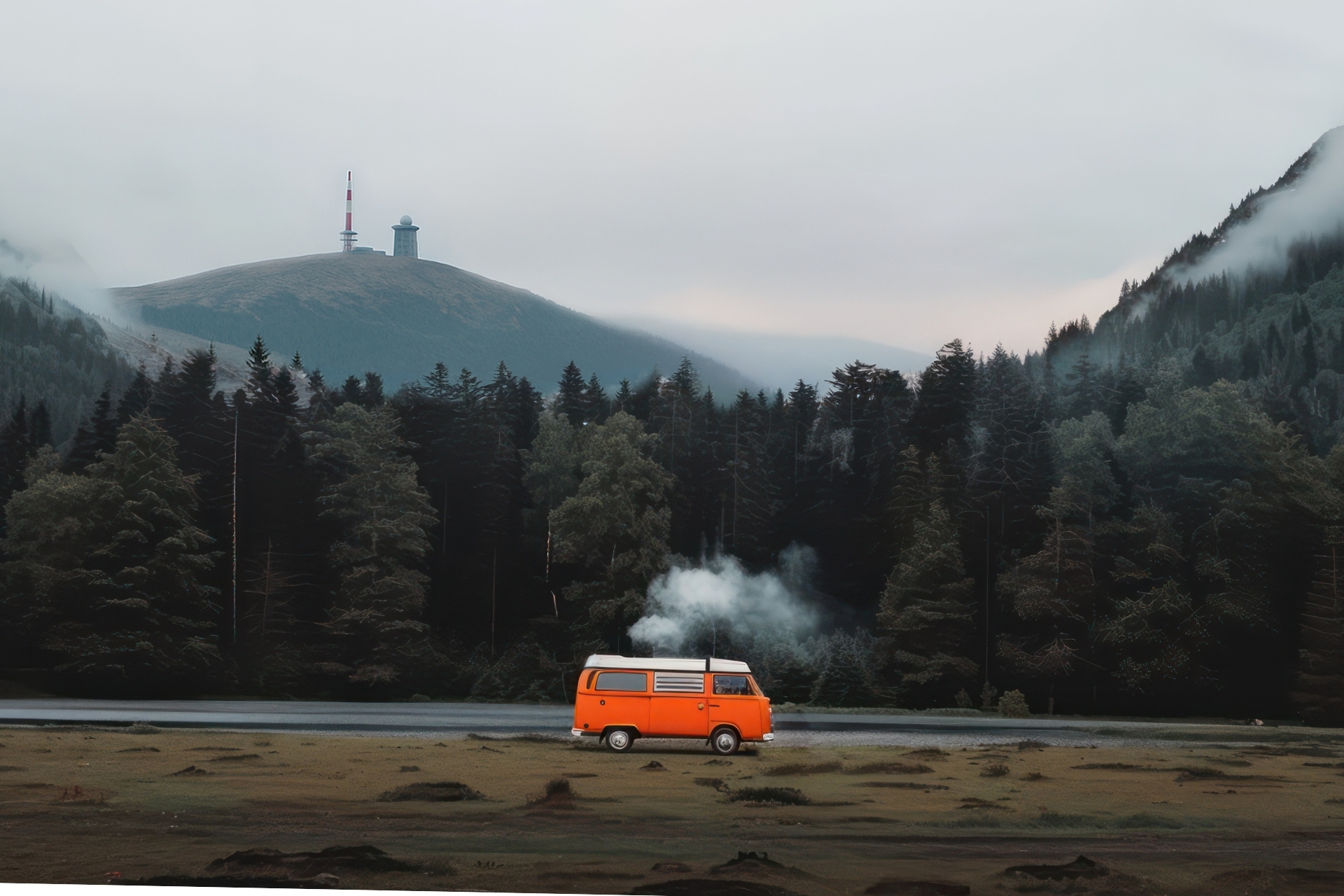 Orangefarbener VW-Bus parkt am Ufer eines Sees, umgeben von dichten Wäldern und Bergen unter einem bewölkten Himmel.