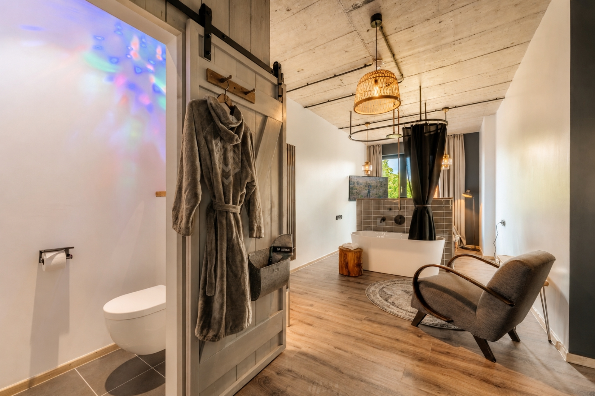 Badezimmer mit Dusche, freistehender Badewanne und gemütlicher Sitzecke. Weiche Textilien und modernes Design.
