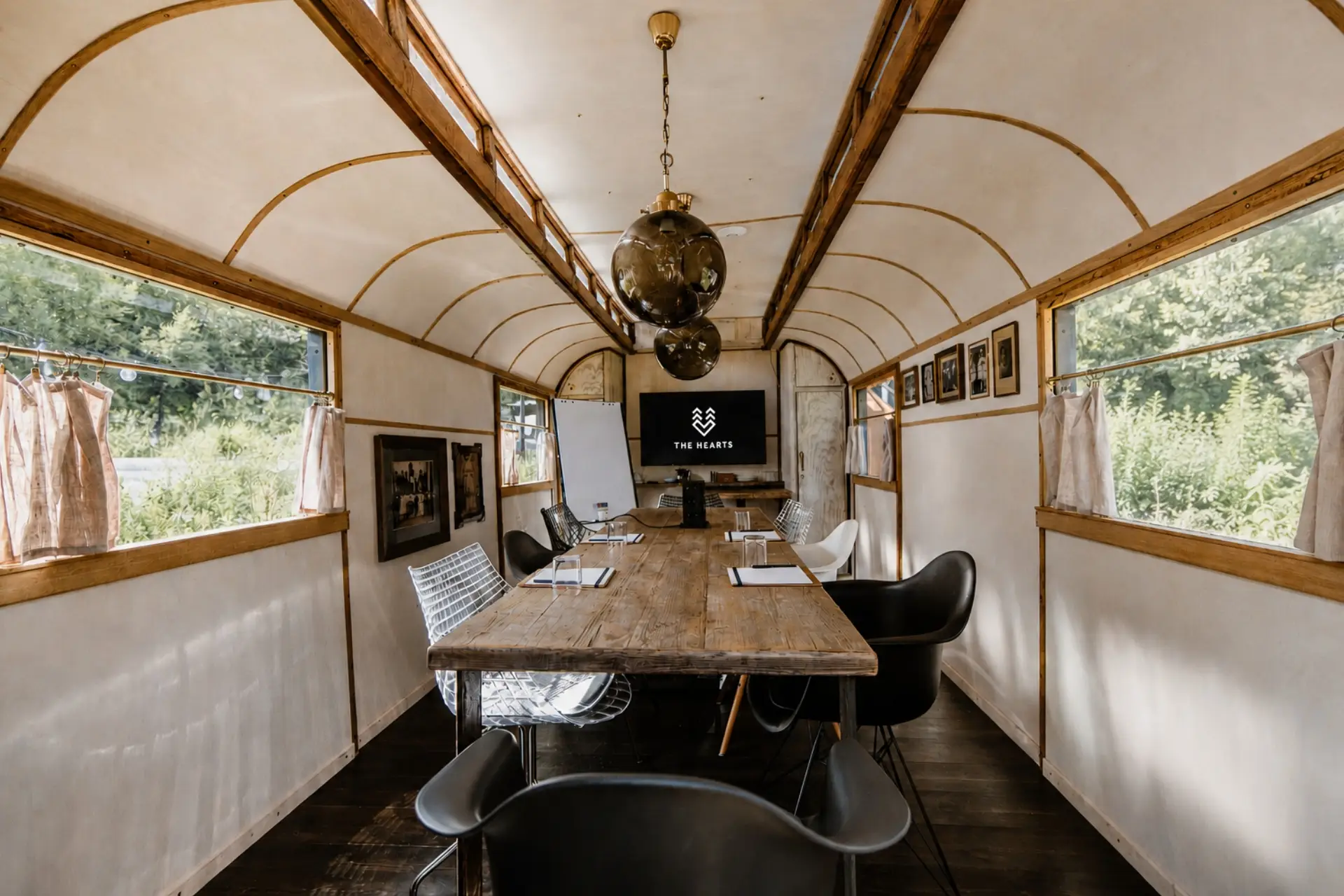 Besprechungsraum in einem umgebauten Zugwagen mit Holztisch, modernen Stühlen und Präsentationsbildschirm. Lichtdurchflutet.