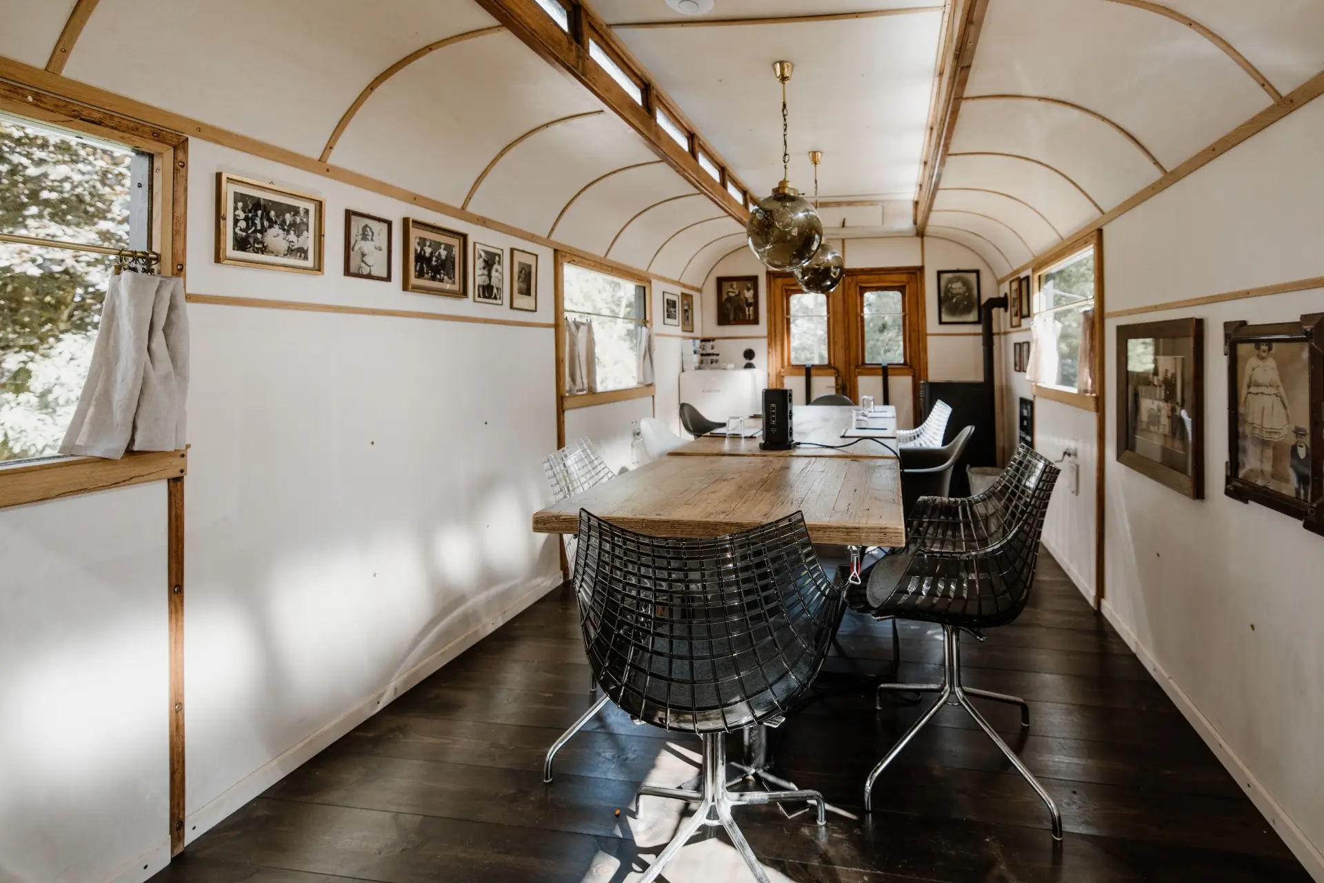 Moderne Besprechungsraum mit Holztisch, schwarzen Stühlen, Fenstern mit Vorhängen und historischen Bildern an der Wand.