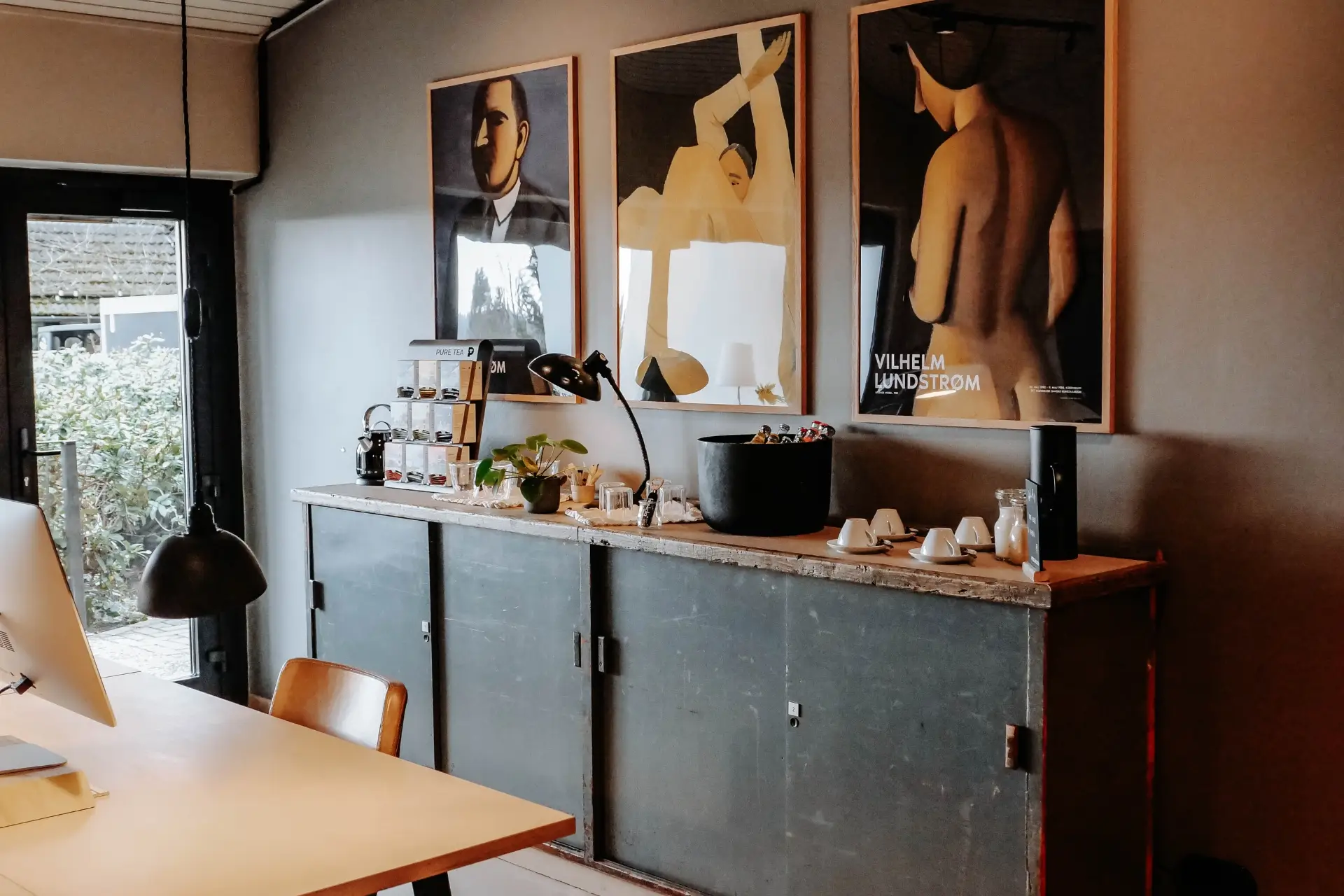Ein modernes Café mit einem großen Holzschrank, dekoriert mit Kunstwerken und einem Tisch für Getränke.